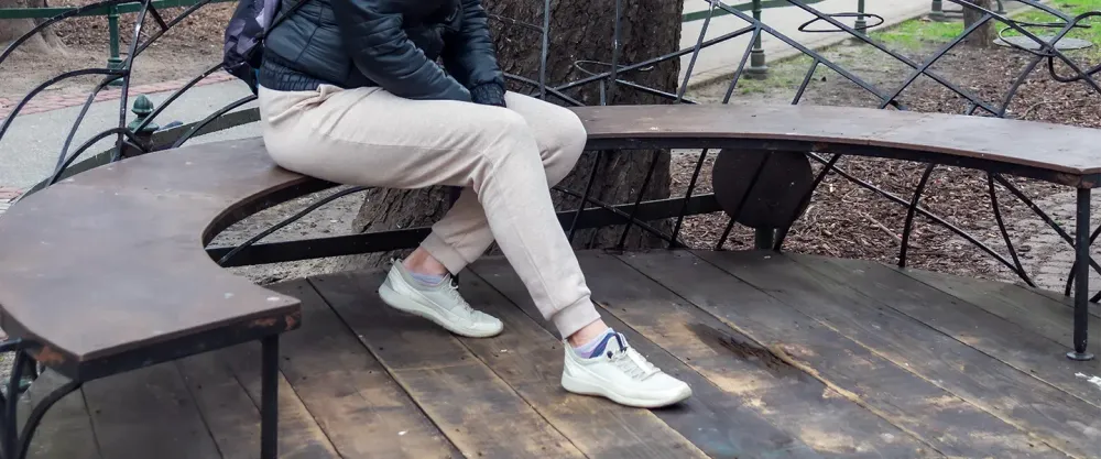 Woman sitting on a park bench in sweatpants
